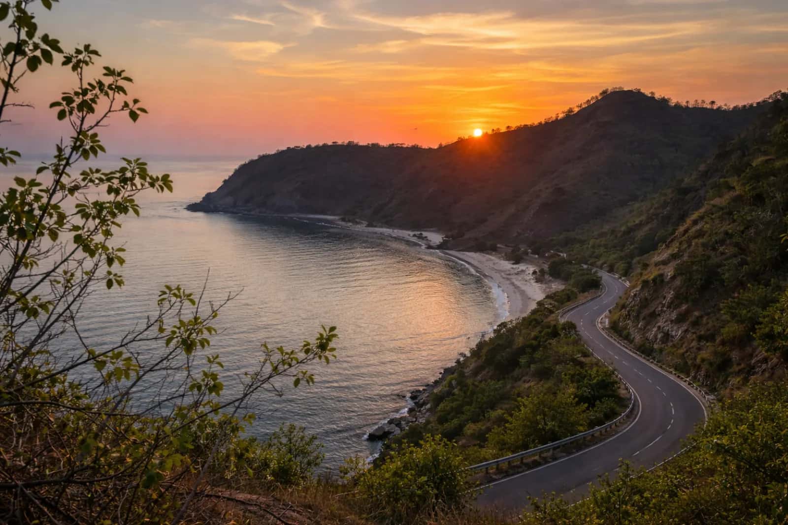 Coastal road winding above a quiet bay at sunset on Timor-Leste's north coast