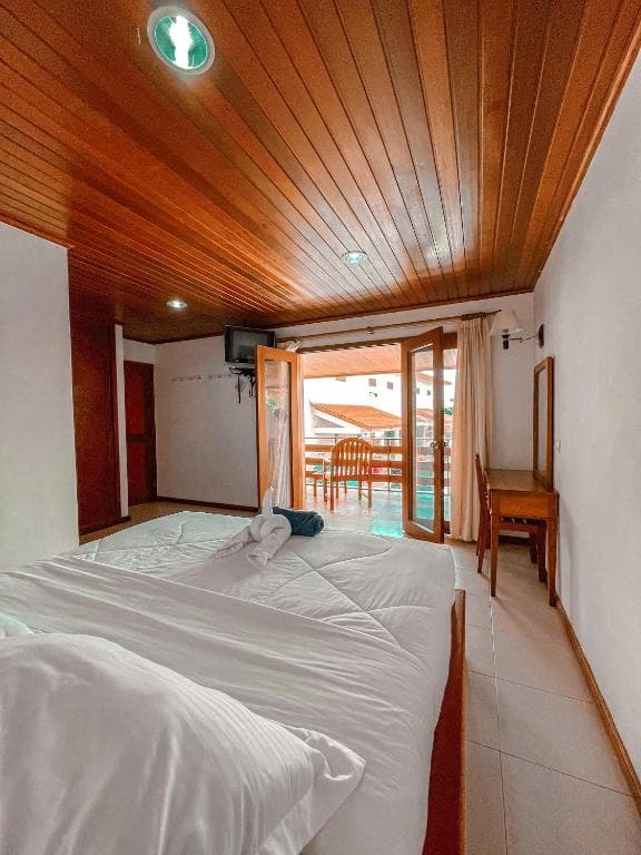 Arbiru Beach Resort bedroom with wood-panelled ceiling and private balcony to the terrace