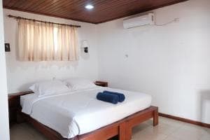 Arbiru Beach Resort bedroom with king bed, AC and curtained window