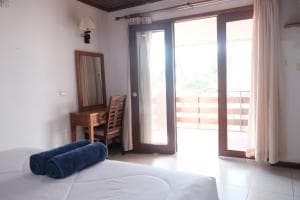 Arbiru Beach Resort suite with bedside table and balcony access