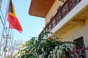Arbiru Beach Resort facade with Timor-Leste flag and bougainvillea