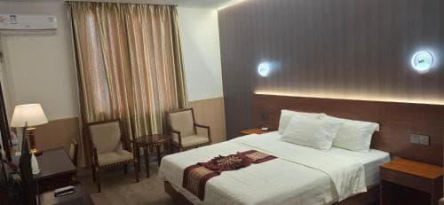 Beach Garden Hotel suite with king bed, seating area and curtained windows