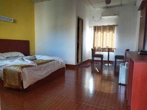 Chong Ti Hotel bedroom with dark wood furniture and yellow accent