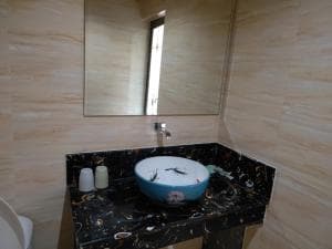 Chong Ti Hotel vanity with blue glass vessel basin on dark marble counter