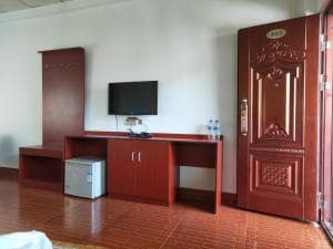 Chong Ti Hotel bedroom with TV cabinet, mini fridge and red wooden door
