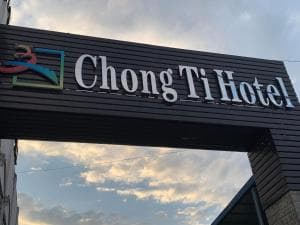 Chong Ti Hotel illuminated signboard at street entrance at dusk