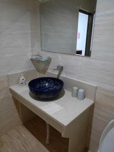 Chong Ti Hotel vanity with blue vessel basin on cream stone counter