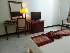 Excelsior Resort writing desk and TV cabinet with welcome towels on bed
