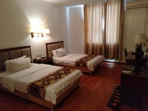Excelsior Resort twin-bed suite with timber floors and curtained windows