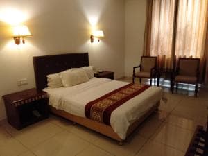 Excelsior Resort room with king bed, two armchairs and timber floors