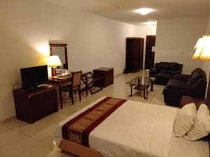 Excelsior Resort suite with sofa, work desk, king bed and TV