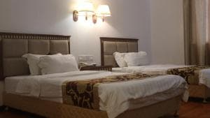 Excelsior Resort twin-bed room with white linens and patterned runners