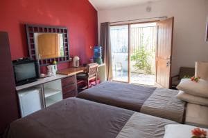 Hotel Esplanada twin-bed room with red accent wall, TV and balcony view
