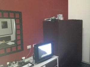 Hotel Esplanada room TV cabinet against red accent wall with framed mirror