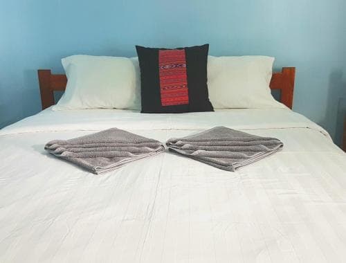 Lauhata Beach Escape bed turned down with welcome cushion and folded towels