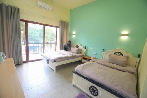M Y Hotel bedroom with green accent wall, twin beds and balcony