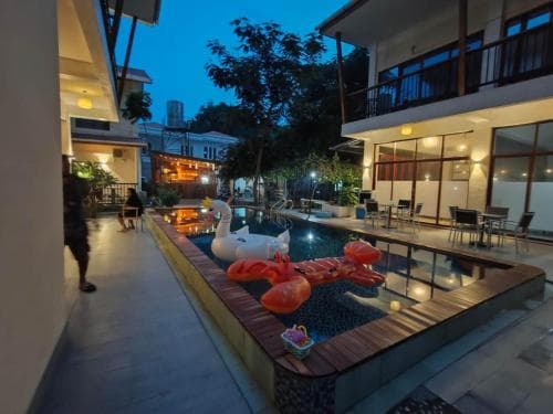 M Y Hotel courtyard at dusk with pool, lawn and illuminated lanterns