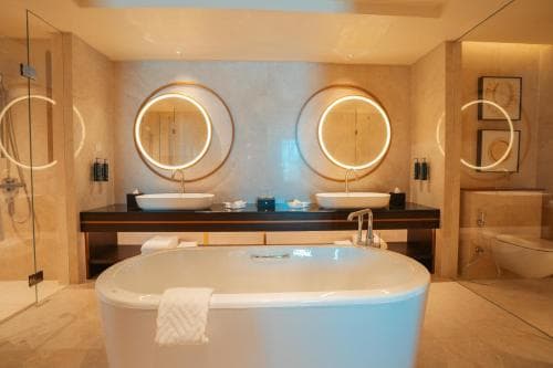 Palm Springs Hotel luxury bathroom with freestanding tub and dual round mirrors