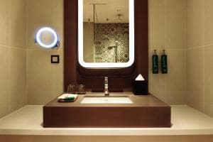 Palm Springs Hotel bathroom with circular illuminated mirror and concrete vanity