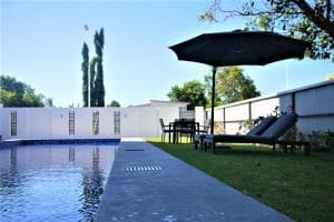 Plaza Hotel Dili pool with parasols, palms and white-painted walls