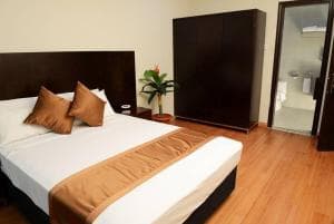 Plaza Hotel Dili bedroom with king bed, dark wardrobe and ensuite