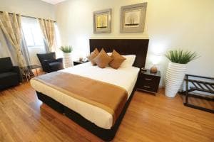 Plaza Hotel Dili bedroom with king bed, twin lamps and reading chair